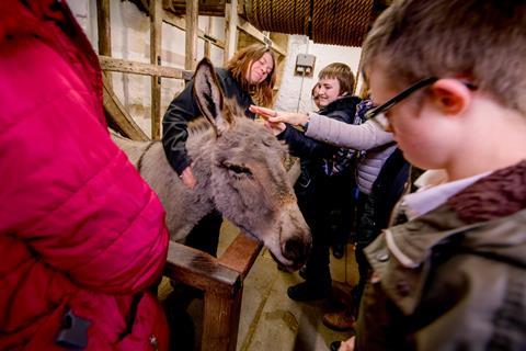 Visiting school children greet Carisbrooke Castle's resident donkey on the Isle of Wight